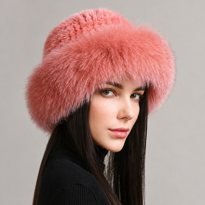 Pink knitted mink hat with a fluffy fox fur brim, shown from the side on a model.