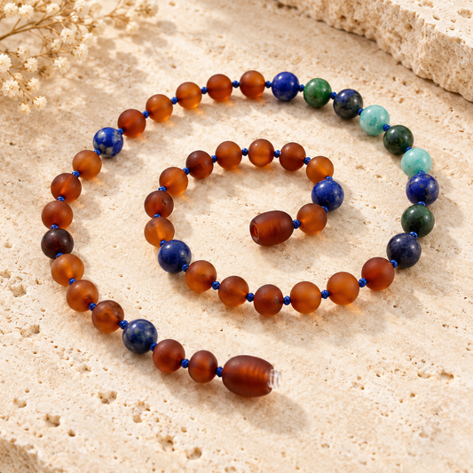 Raw cognac Baltic amber and lapis lazuli necklace on beige stone