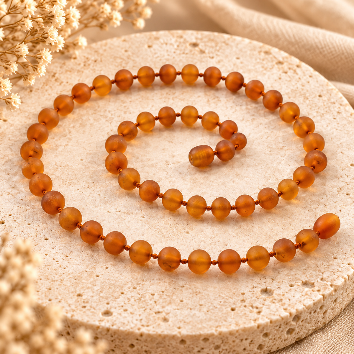 Raw cognac Baltic amber necklace on warm beige stone